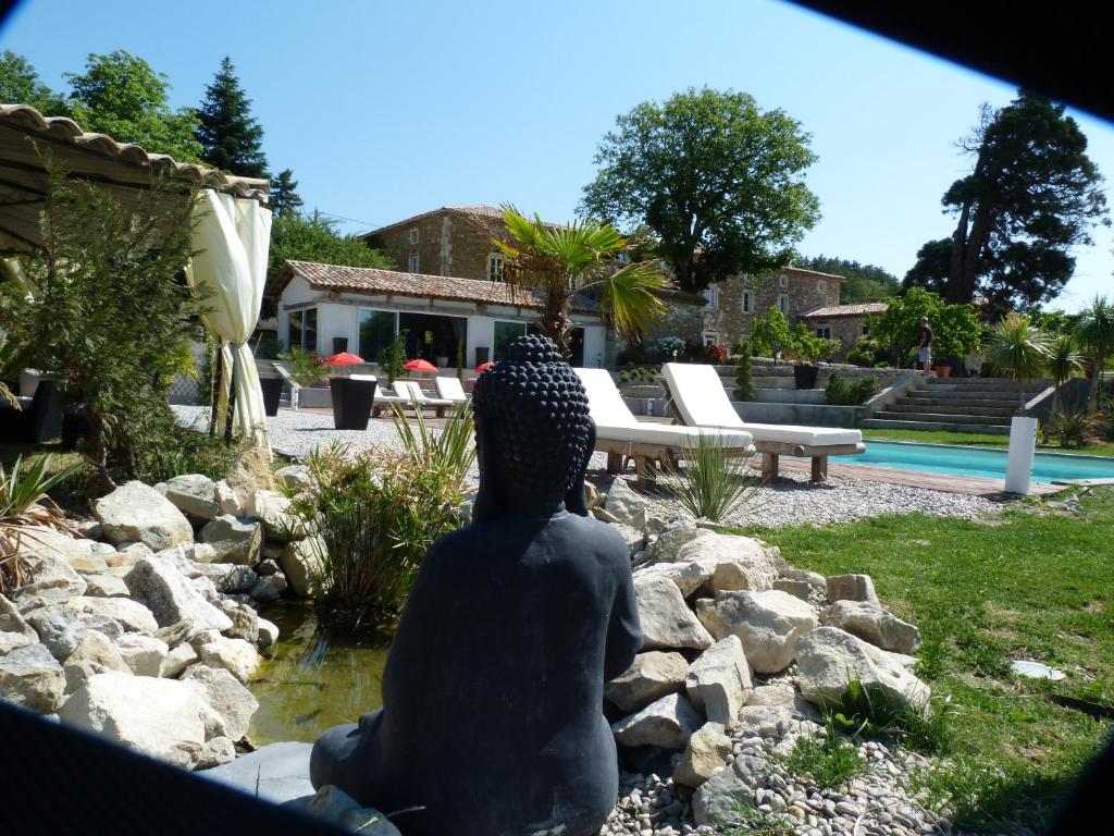 a statue of a person sitting next to a pool at Le Prieuré des Sources in La Répara