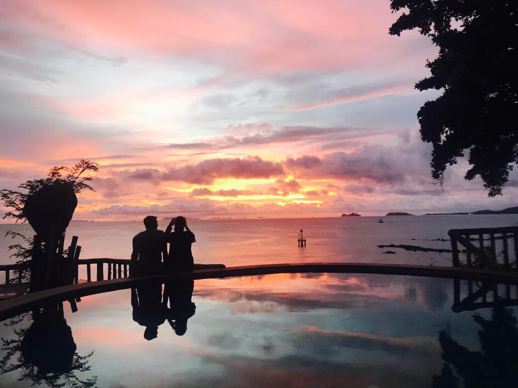 a couple standing in front of a pool at sunset at Suncliff Resort in Haad Rin