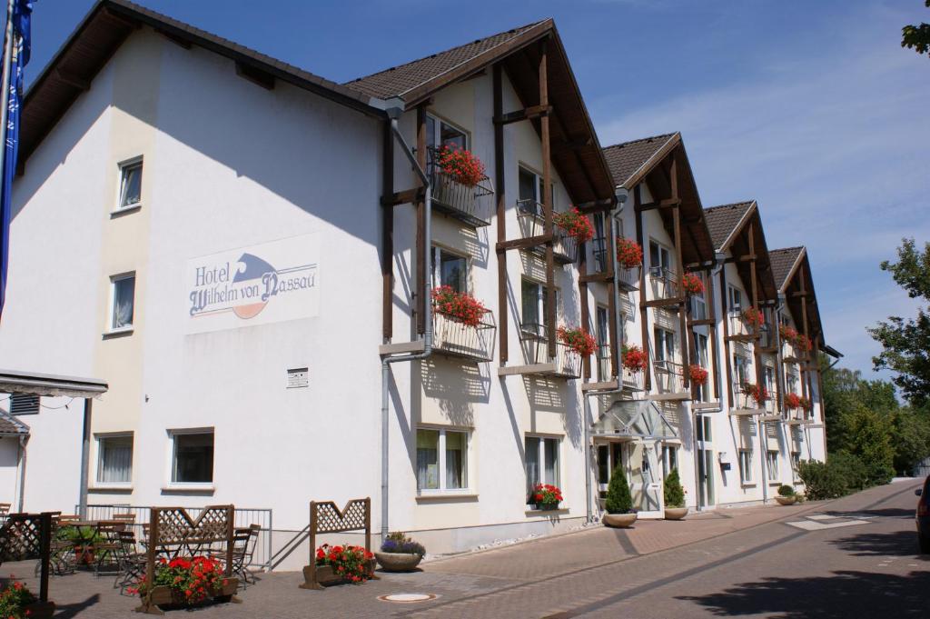 ein großes weißes Gebäude mit Blumen an den Fenstern in der Unterkunft Hotel & Restaurant Wilhelm von Nassau in Diez