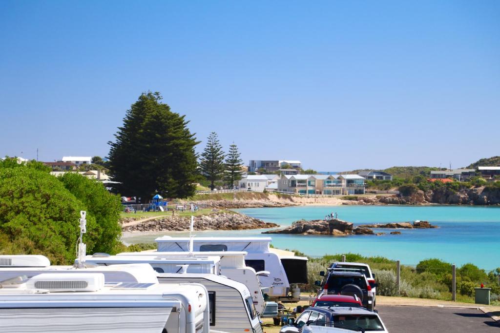 a bunch of rvs parked in a parking lot next to a beach at Sea Vu Caravan Park in Robe