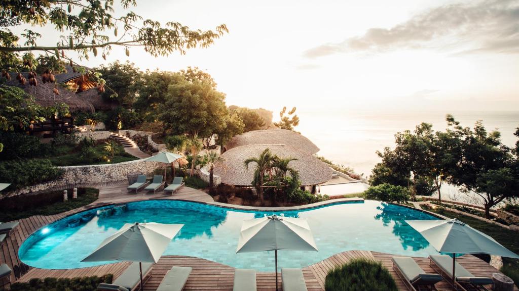 a swimming pool with chairs and umbrellas at a resort at Suarga Padang Padang in Uluwatu