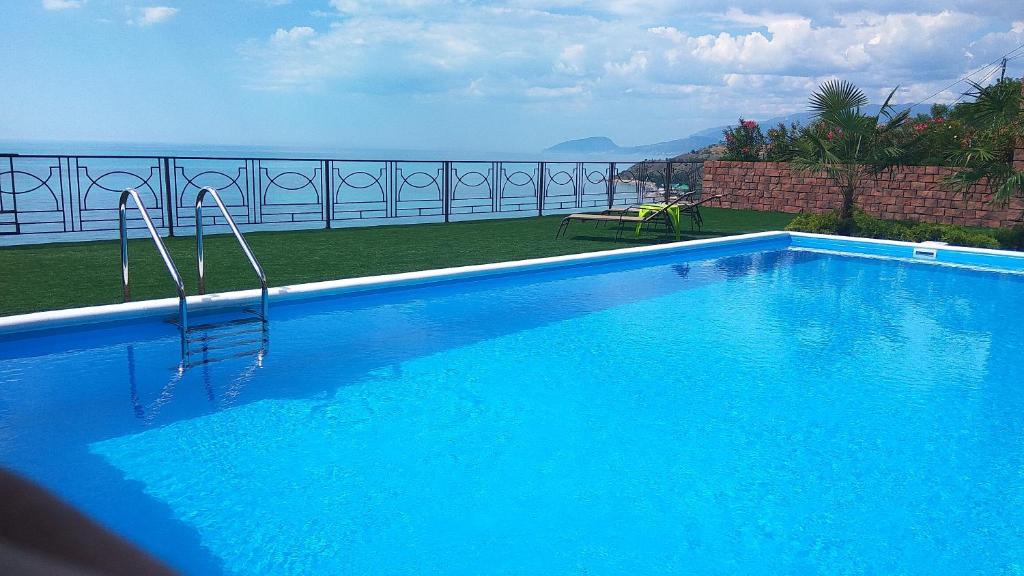 a large blue swimming pool with a view of the ocean at Guest House Panorama in Malorechenskoye