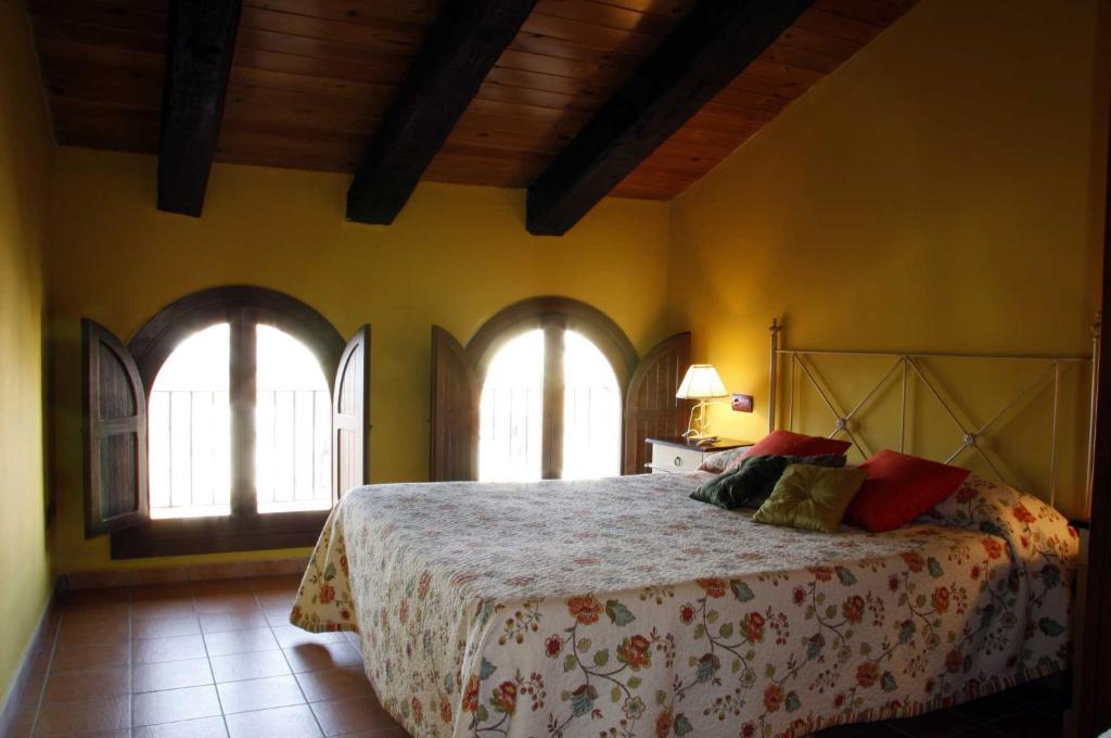 um quarto com uma cama grande e 2 janelas em Apartamentos El Canonigo de Teruel em Teruel