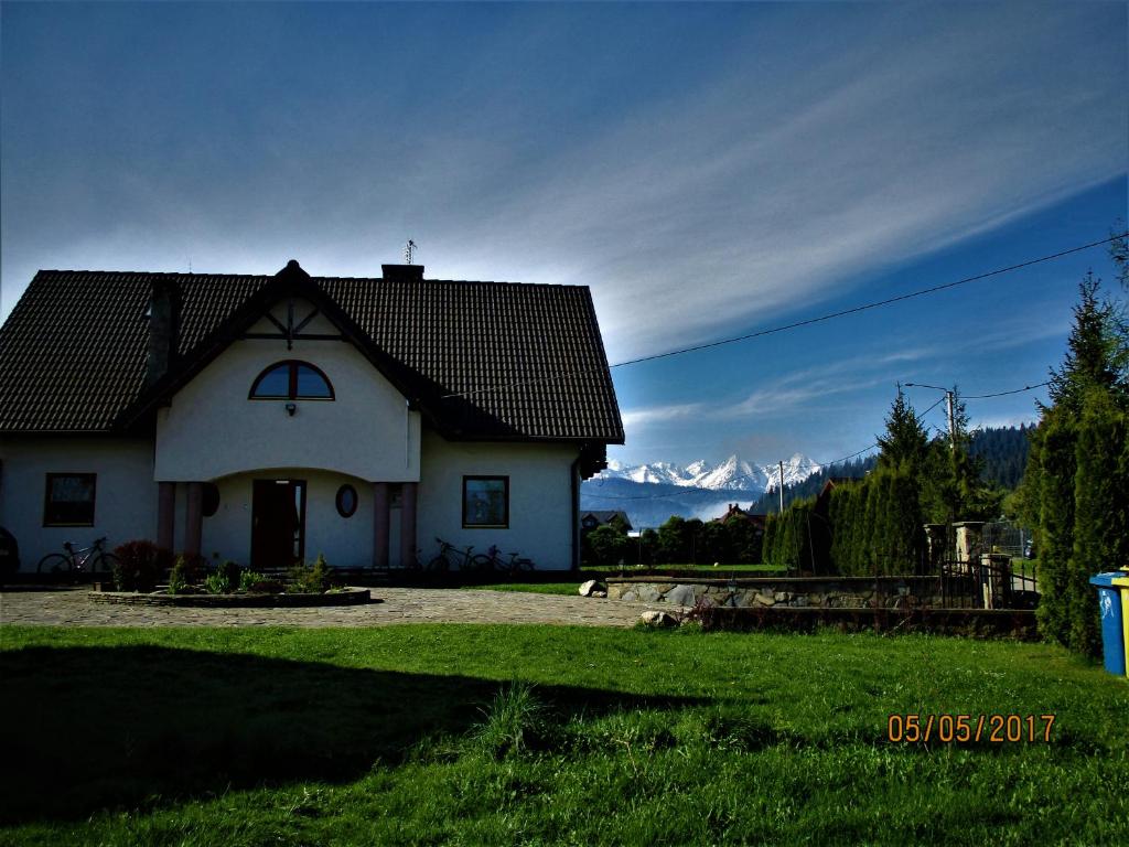 a small white house with mountains in the background at Agroturystyka nad brzegiem in Kacwin