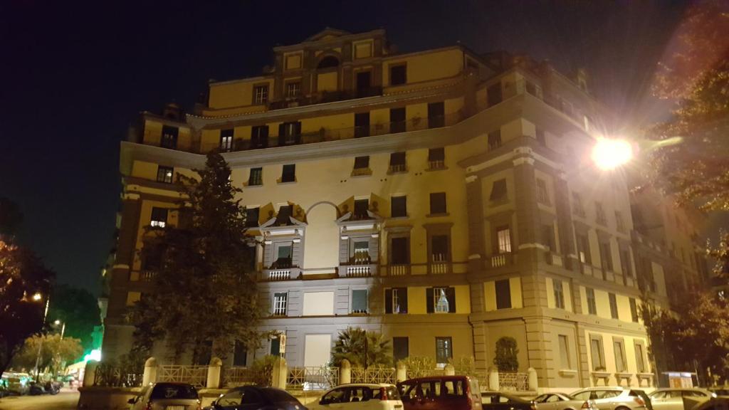 een groot gebouw 's nachts met auto's geparkeerd voor bij Affittacamere Mazzini in Rome