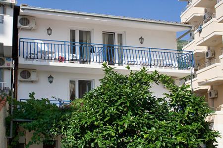 a white building with a blue balcony on it at Apartments Vila Nikolić Rafailovići in Rafailovici