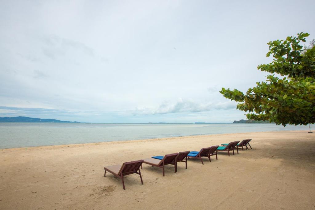 a row of chairs sitting on a beach at Da Kanda Villa Beach Resort in Thong Sala