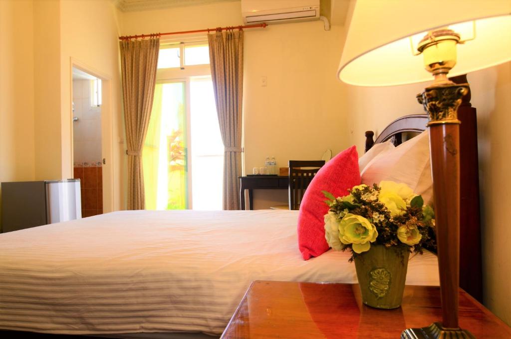 a bedroom with a bed with a lamp and flowers on a table at East of Love Homestay in Hualien City