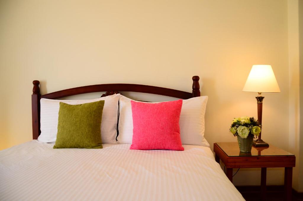 a bedroom with a bed with colorful pillows and a lamp at East of Love Homestay in Hualien City