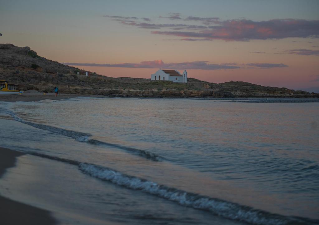 a beach with a house on top of a hill at Ammos Sea Front Rooms - Adults only in Vasilikos