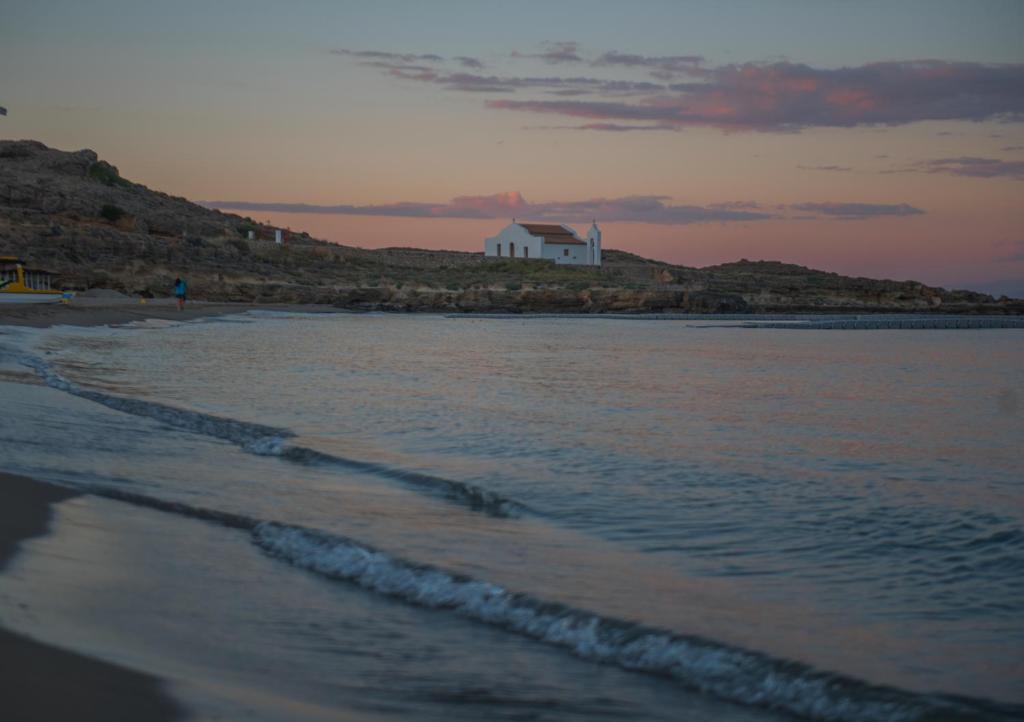 a beach with a house on top of a hill at Ammos Beachfront Confortable Rooms - Adults only in Vasilikos