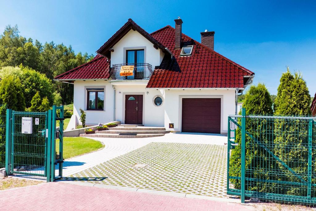ein Haus mit einem roten Dach und einem Tor in der Unterkunft Dom Wakacyjny Quattro Niesulice in Niesulice