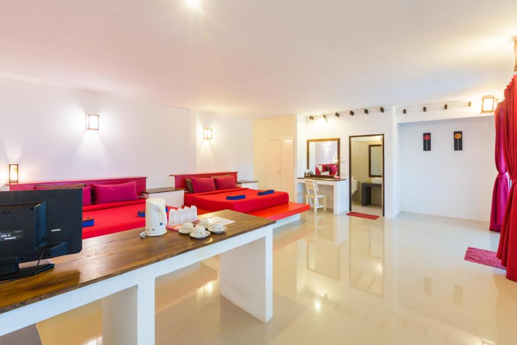 a living room with a red couch and a tv at Da Kanda Villa Beach Resort in Thong Sala