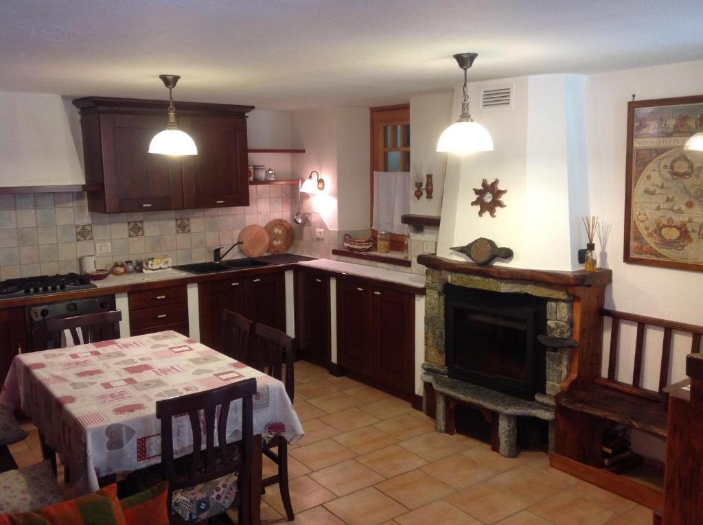 a kitchen with a table and a fireplace at B&B Le Temps d'une Pause in Champorcher