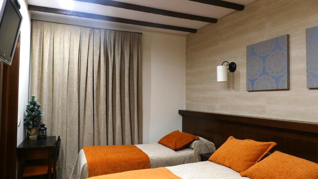 a hotel room with two beds and a window at Hotel Rural La Cabrera in Robledo del Buey