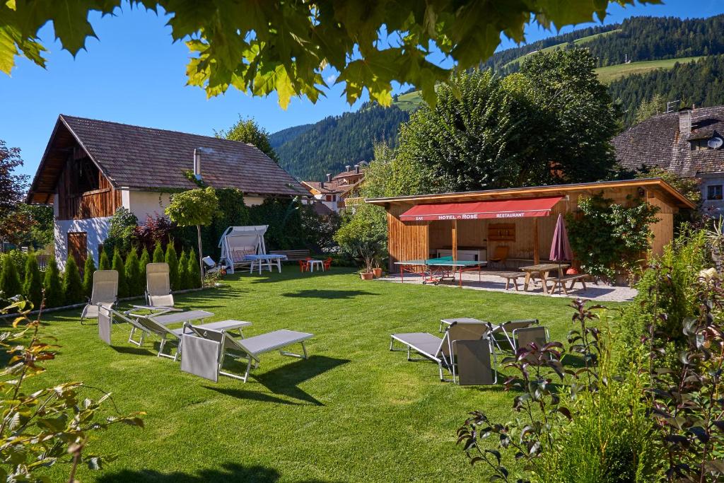 um quintal com cadeiras e mesas e uma casa em Hotel Rose em Villabassa
