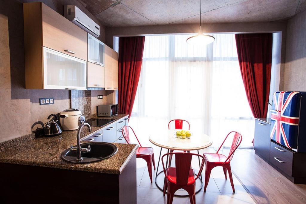 a kitchen with a table and red chairs and a kitchen with a sink at Apartment near the sea in Gribovka
