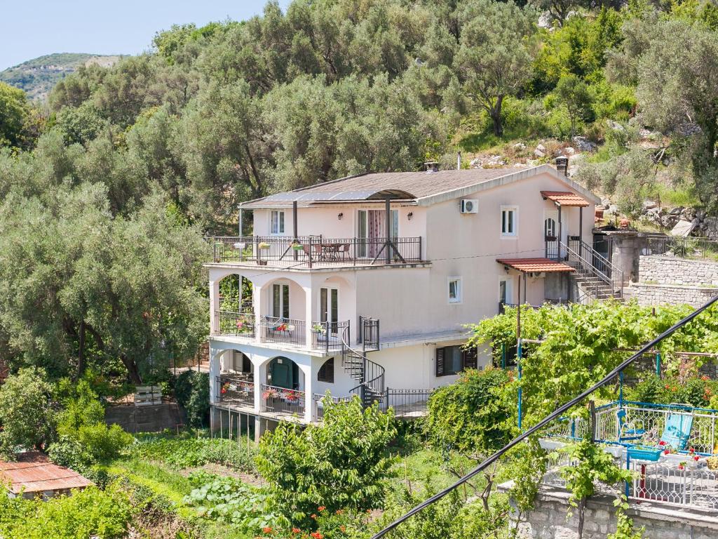 una gran casa blanca en una colina con árboles en Apartments Midžor, en Petrovac na Moru