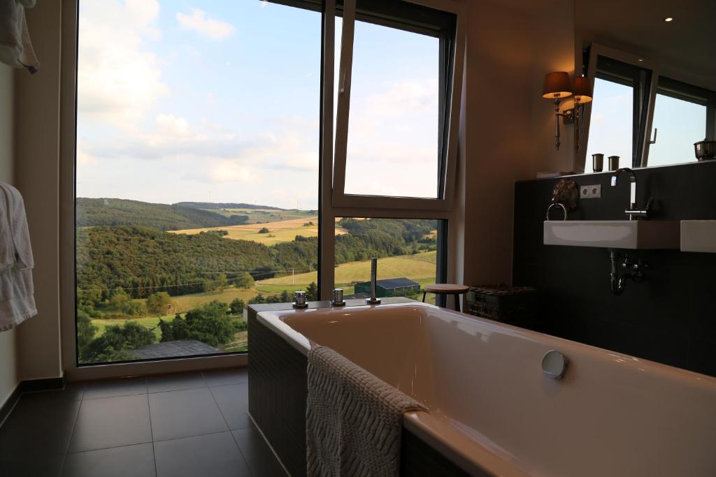 La salle de bains est pourvue d'une baignoire et d'une grande fenêtre. dans l'établissement Ferienhaus zur Burg Olbruck, à Hain