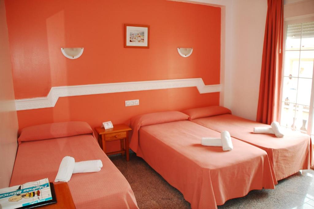 2 camas en una habitación con paredes de color naranja en Hostal Mary Tere, en Salobreña