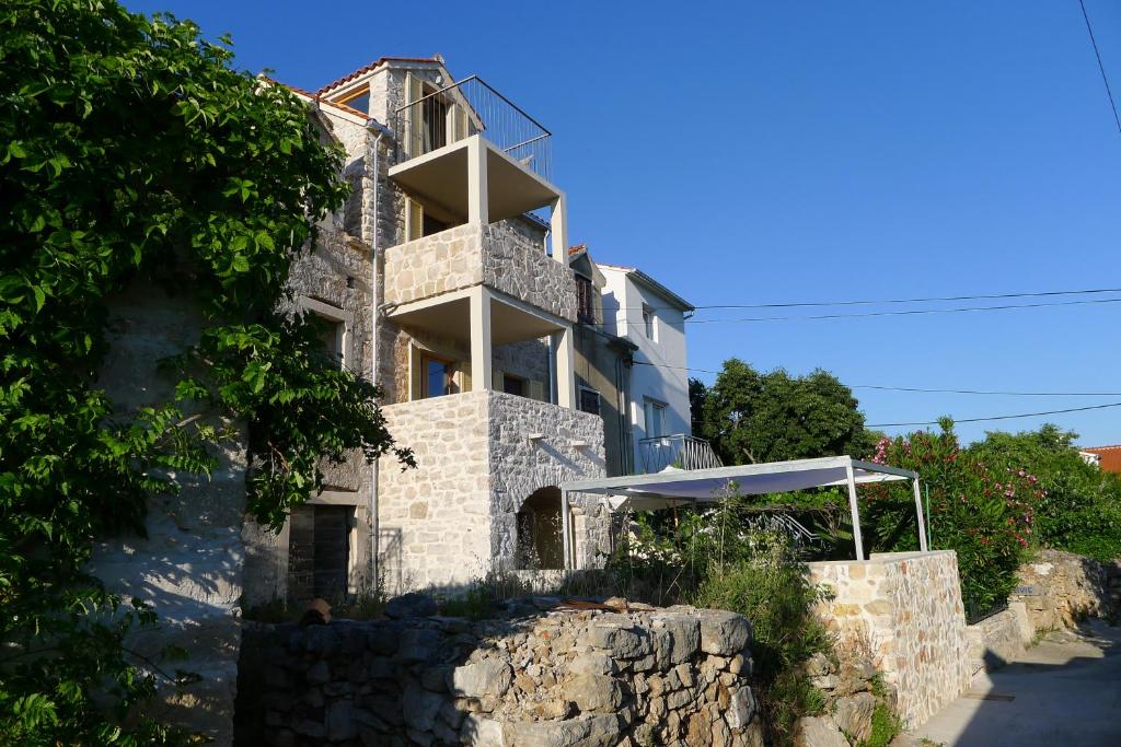 um edifício com uma varanda no topo de uma parede de pedra em Stone House Nana em Zlarin