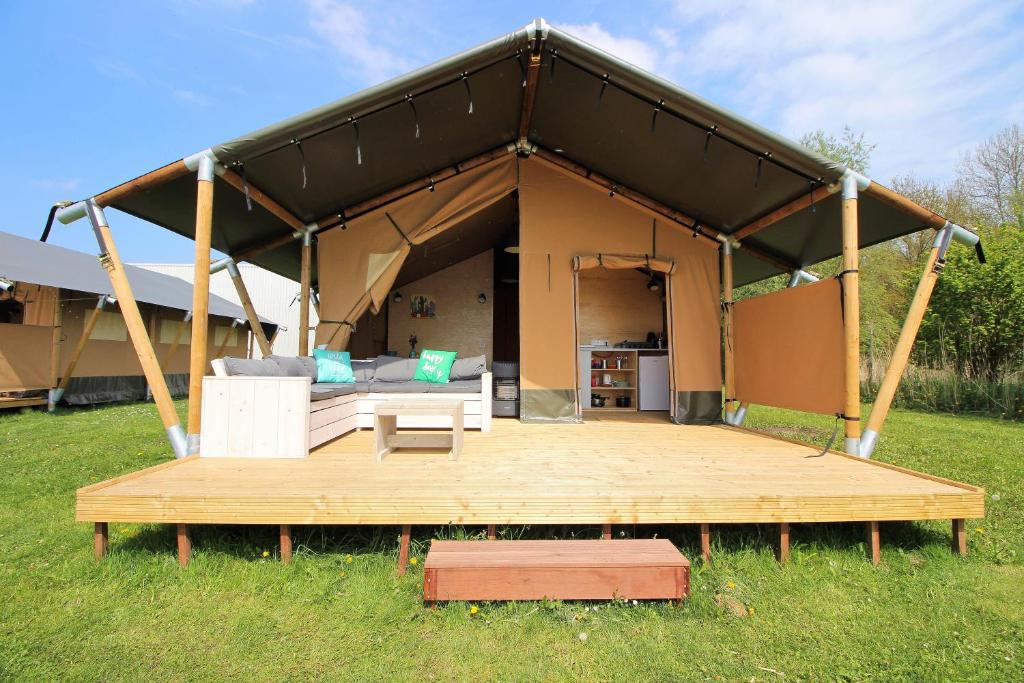 a large tent with a deck in a field at Camping Marina Eemhof in Zeewolde