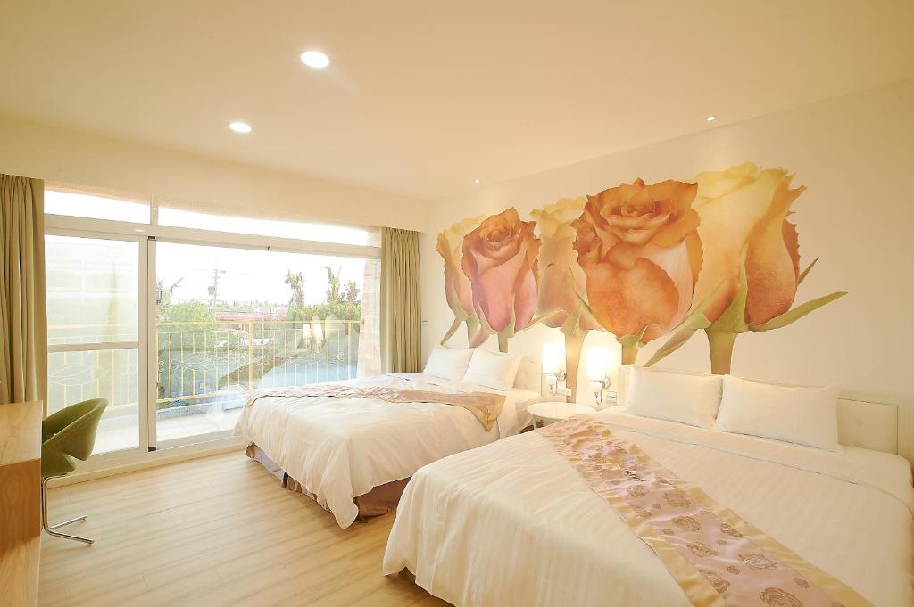 sypialnia z 2 łóżkami i malowidłem kwiatowym w obiekcie Top Bay B&B w mieście Donggang