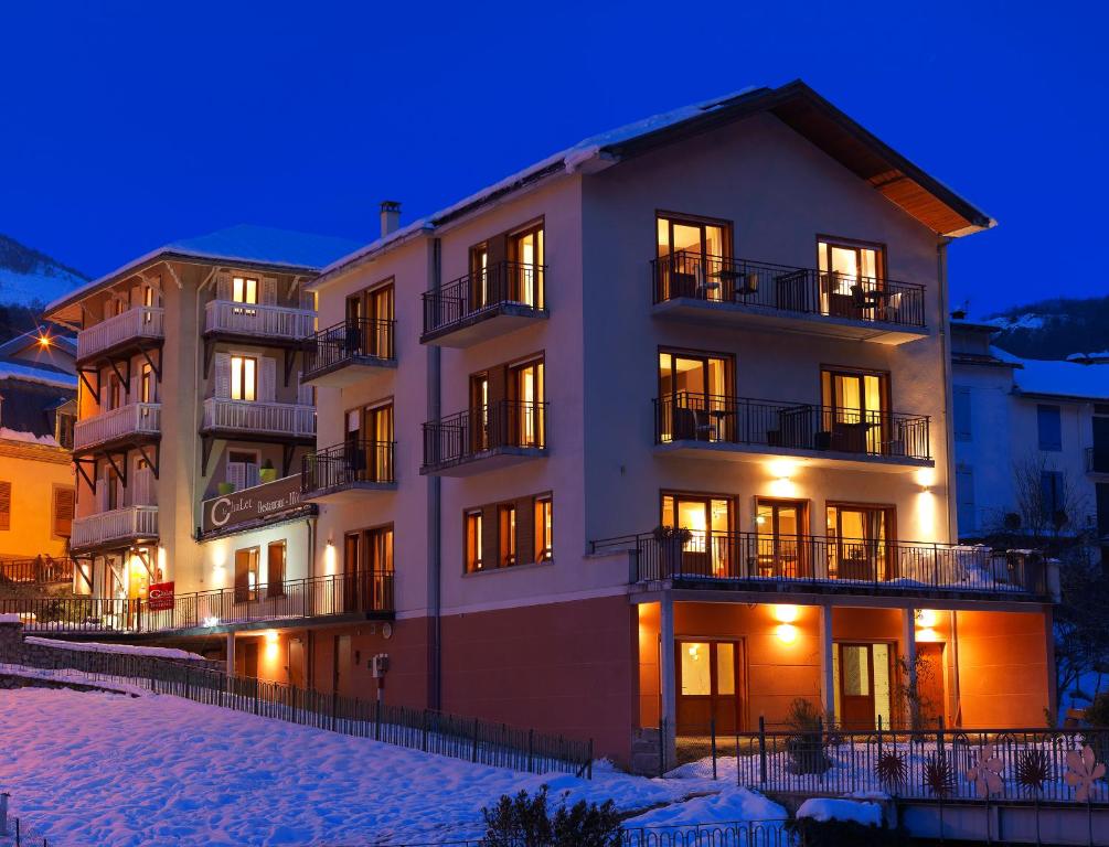 un gran edificio en la nieve por la noche en Hôtel Le Chalet en Ax-les-Thermes