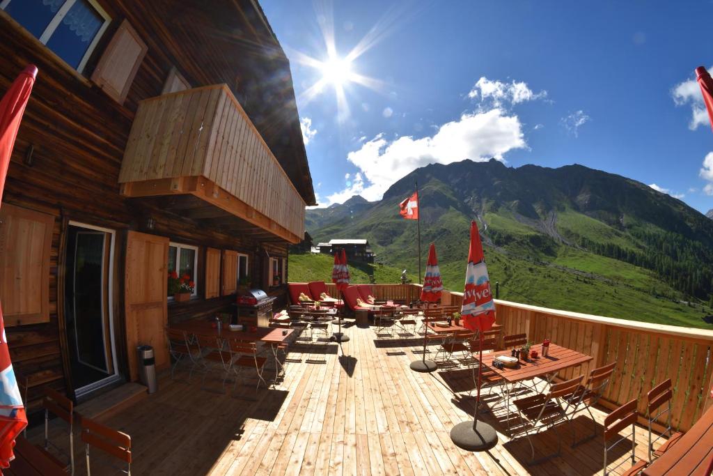 a wooden deck with chairs and tables and a mountain at Berggasthaus-Strassberg in Strassberg