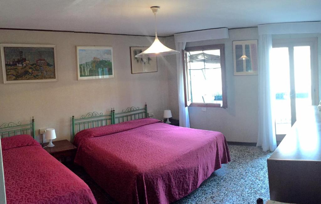 a bedroom with two beds with pink sheets and a window at Antica Locanda Montin in Venice