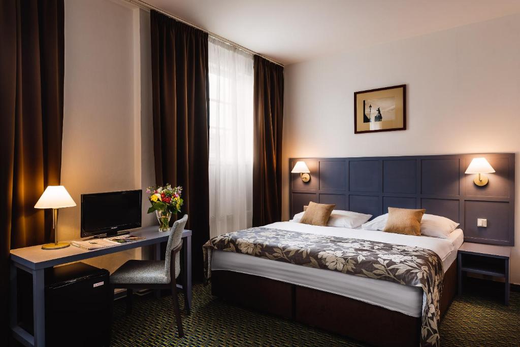 ein Hotelzimmer mit einem Bett, einem Schreibtisch und einem Computer in der Unterkunft Central Hotel Prague in Prag