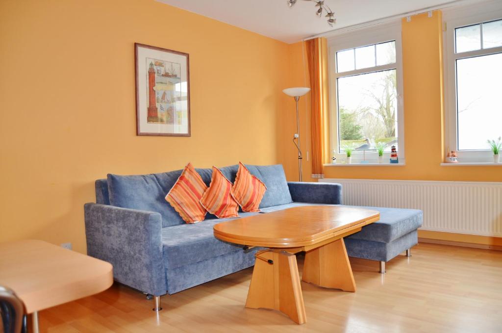a living room with a blue couch and a wooden table at Haus Windrose in Norderney