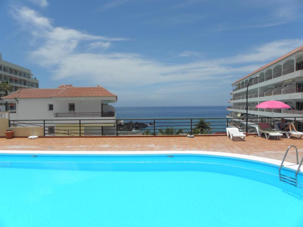 a swimming pool with a view of the ocean at Oceanfront Beach Apartment la Arena in Puerto de Santiago