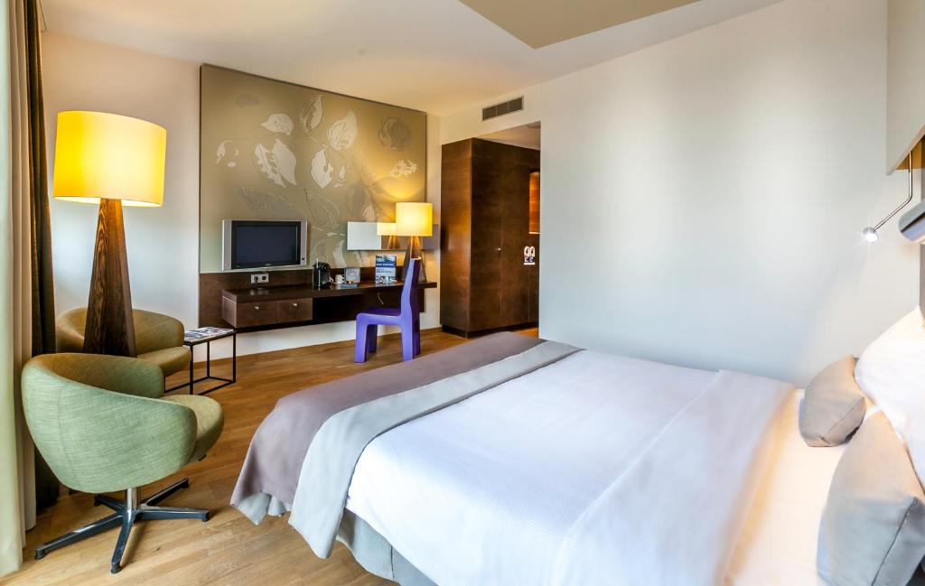Schlafzimmer mit einem Bett, einem Schreibtisch und einem TV in der Unterkunft Hotel Artemis Amsterdam in Amsterdam
