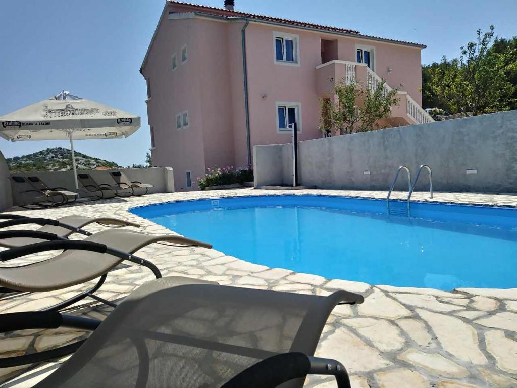 a swimming pool with chairs and an umbrella next to a building at Apartments T&C in Drage