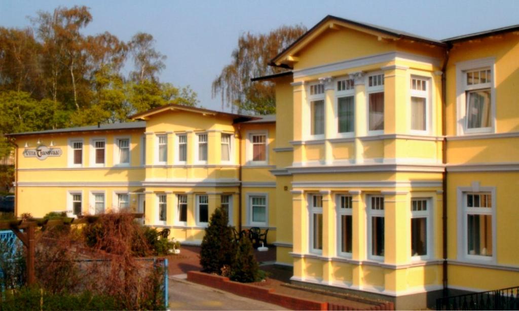 ein großes gelbes Haus mit weißen Säulen in der Unterkunft Pension Villa Transvaal in Ahlbeck