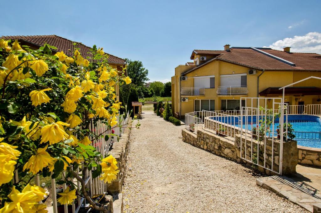 a fence with yellow flowers next to a house at Iskar Villas in Kranevo