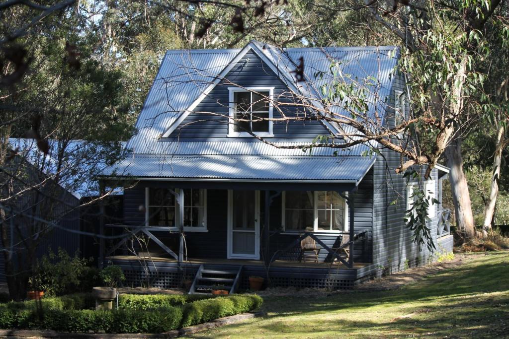 ein blaues Haus mit einem blauen Blechdach in der Unterkunft Cottage At 31 in Bundanoon