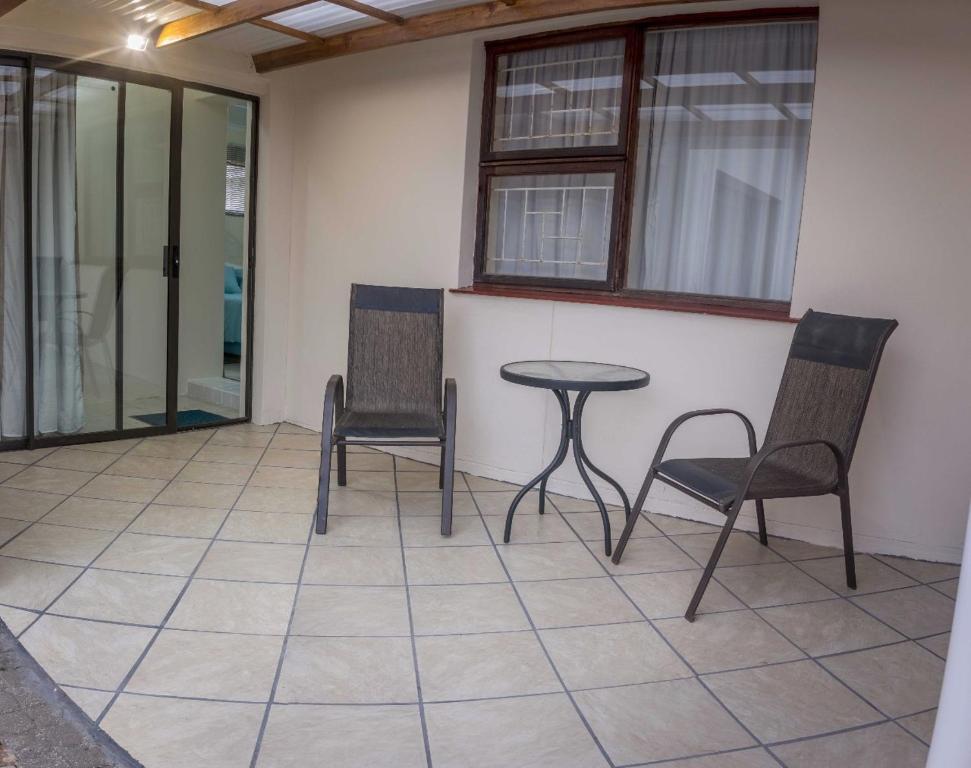 a patio with two chairs and a table and windows at Lientjies Overnight in George