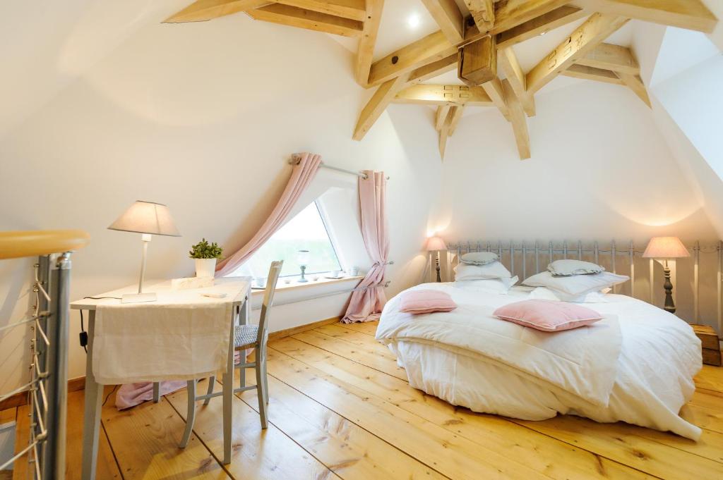 a bedroom with a bed and a table and a window at Les Chambres de Ribeaufontaine in Dorengt