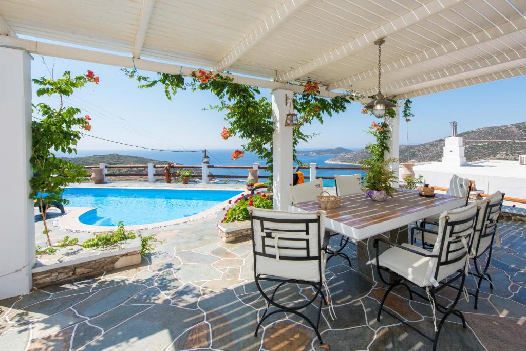 um pátio com uma mesa e cadeiras e uma piscina em Villa Pelagos em Platis Gialos, Sifnos