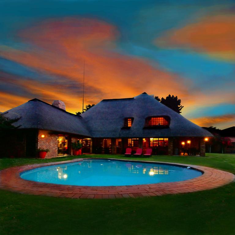 uma casa com uma piscina em frente em African Footprints Lodge em Midrand