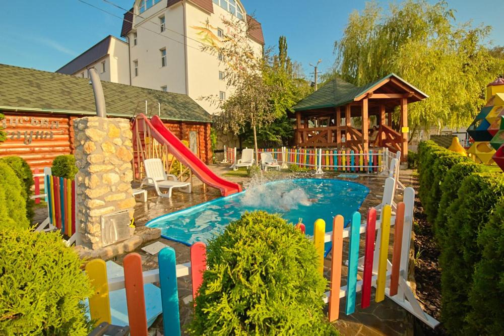a pool in a backyard with a slide and a playground at Hotel Panorama in Kremenetsʼ