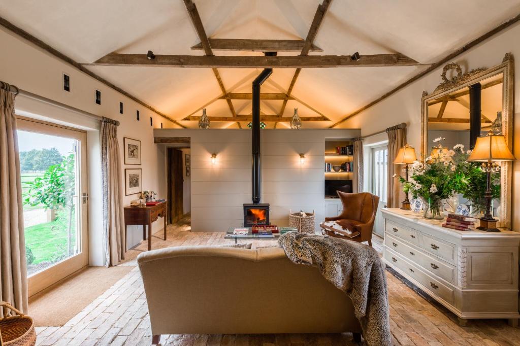 Cambridge Country Cottages في كامبريدج: غرفة معيشة مع أريكة ومدفأة