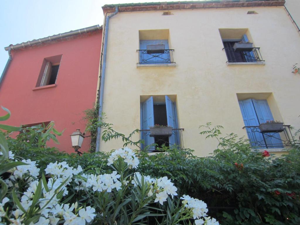 un edificio de apartamentos con ventanas azules y flores en Au Remp'Arts, en Elne