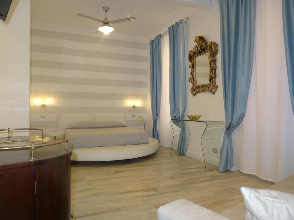サンタ・マルゲリータ・リグレにあるSuites Margotのベッドルーム1室(ベッド1台、鏡、青いカーテン付)
