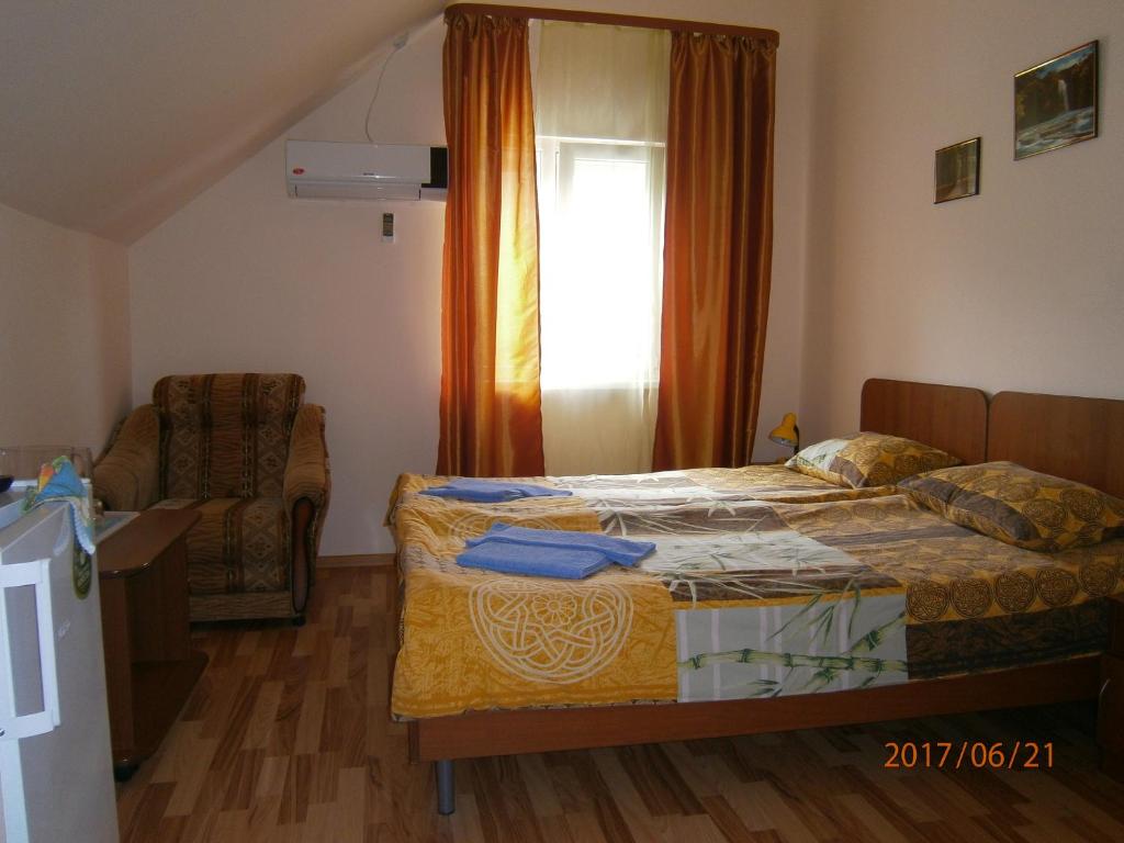 a bedroom with a bed and a chair and a window at Guest house Barhatniy sezon in Novy Afon