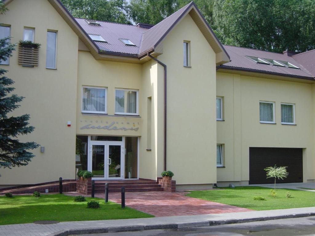 a large white house with a driveway at Hotel Audenis in Birštonas