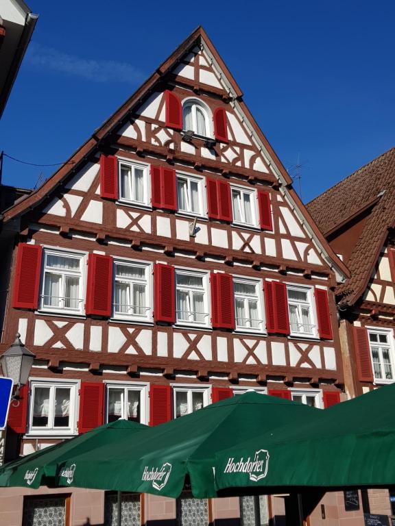 abered building with red windows and a green umbrella at Hotel-Restaurant Ratsstube in Calw