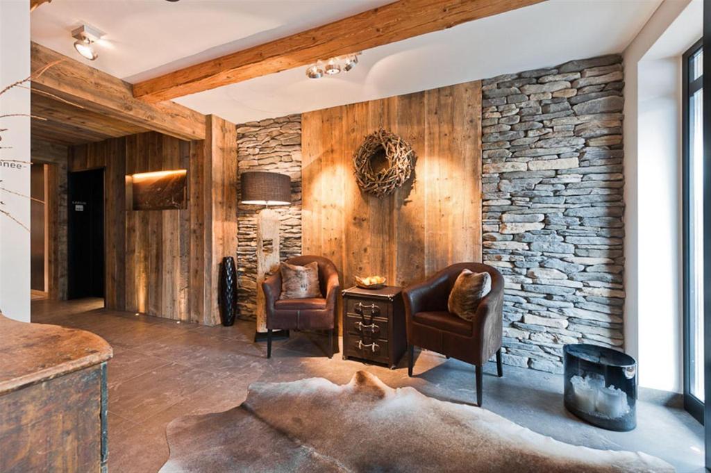 Burgus - Design Suites & Apartments في بورغسيو: غرفة معيشة مع كرسيين وجدار حجري
